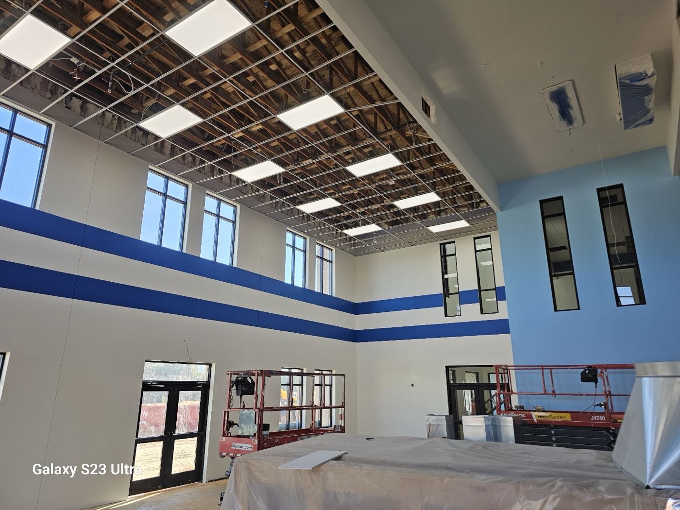 Two-story school atrium with white walls and bold blue stripe bands