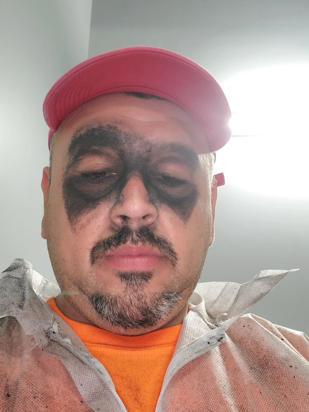 Juan Mario with dark paint around his eyes from a respirator, on a job site
