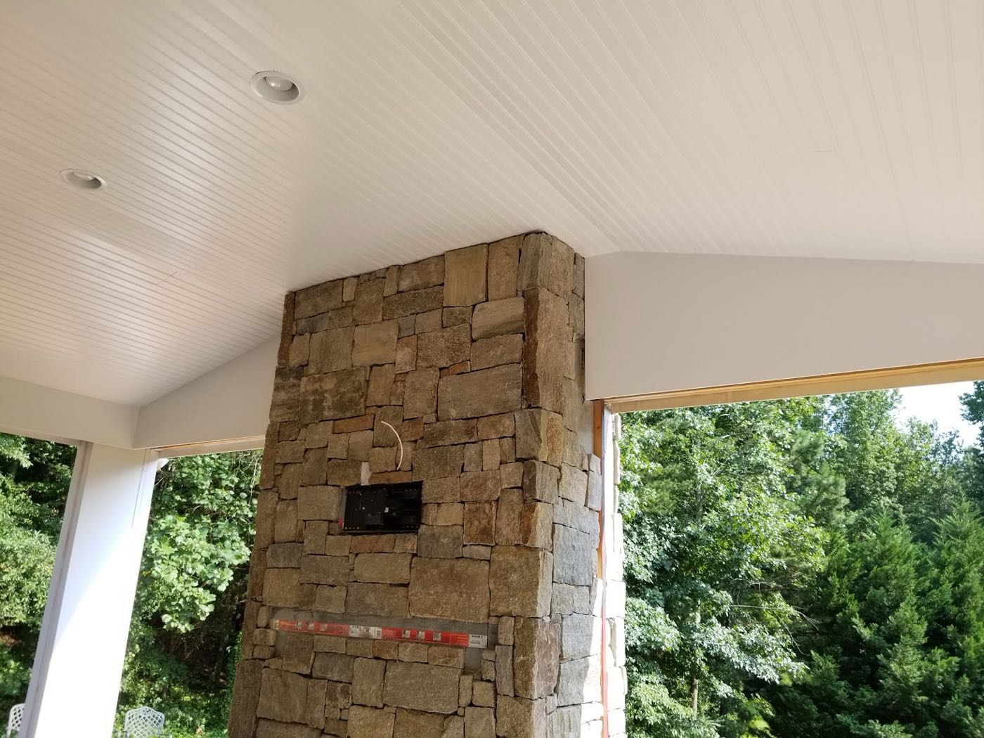 Freshly painted white beadboard porch ceiling meeting a stacked-stone column